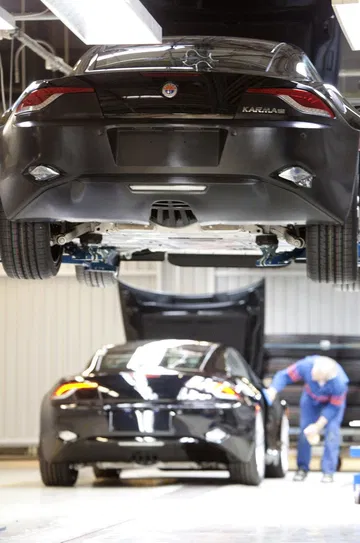 Vista trasera del Fisker Karma elevado en un taller, mostrando suspensión y transmisión.