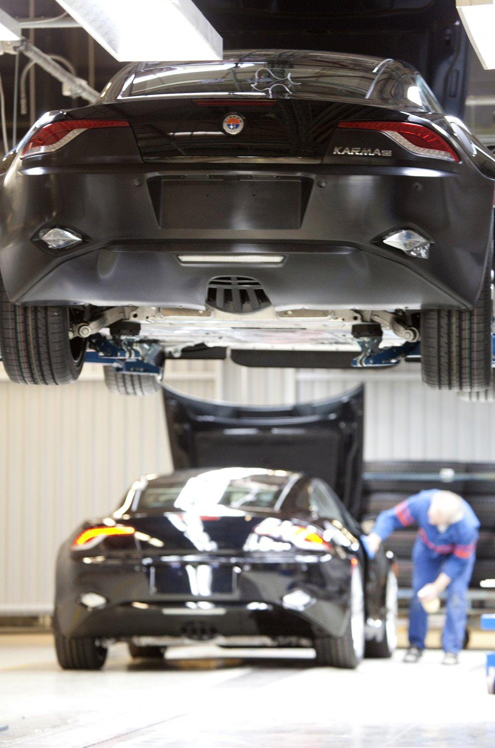 Vista trasera del Fisker Karma elevado en un taller, mostrando suspensión y transmisión.