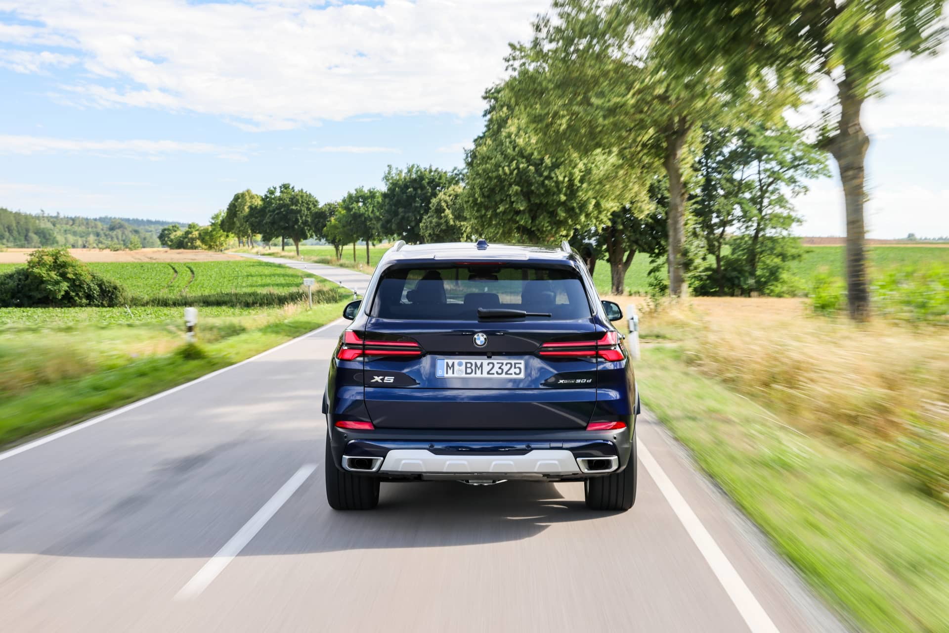 Vista trasera del BMW X5 en carretera, mostrando líneas elegantes y robustas.