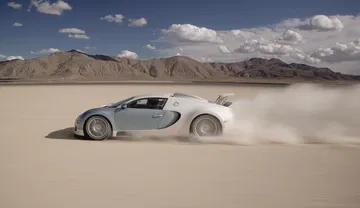 Bugatti Veyron desplegando potencia y velocidad en terreno arenoso.