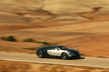 Vista lateral del Bugatti Veyron en plena aceleración en entorno desértico.