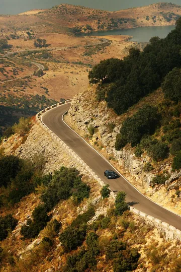 Vista aérea de un Bugatti Veyron en una carretera de montaña serpenteante.