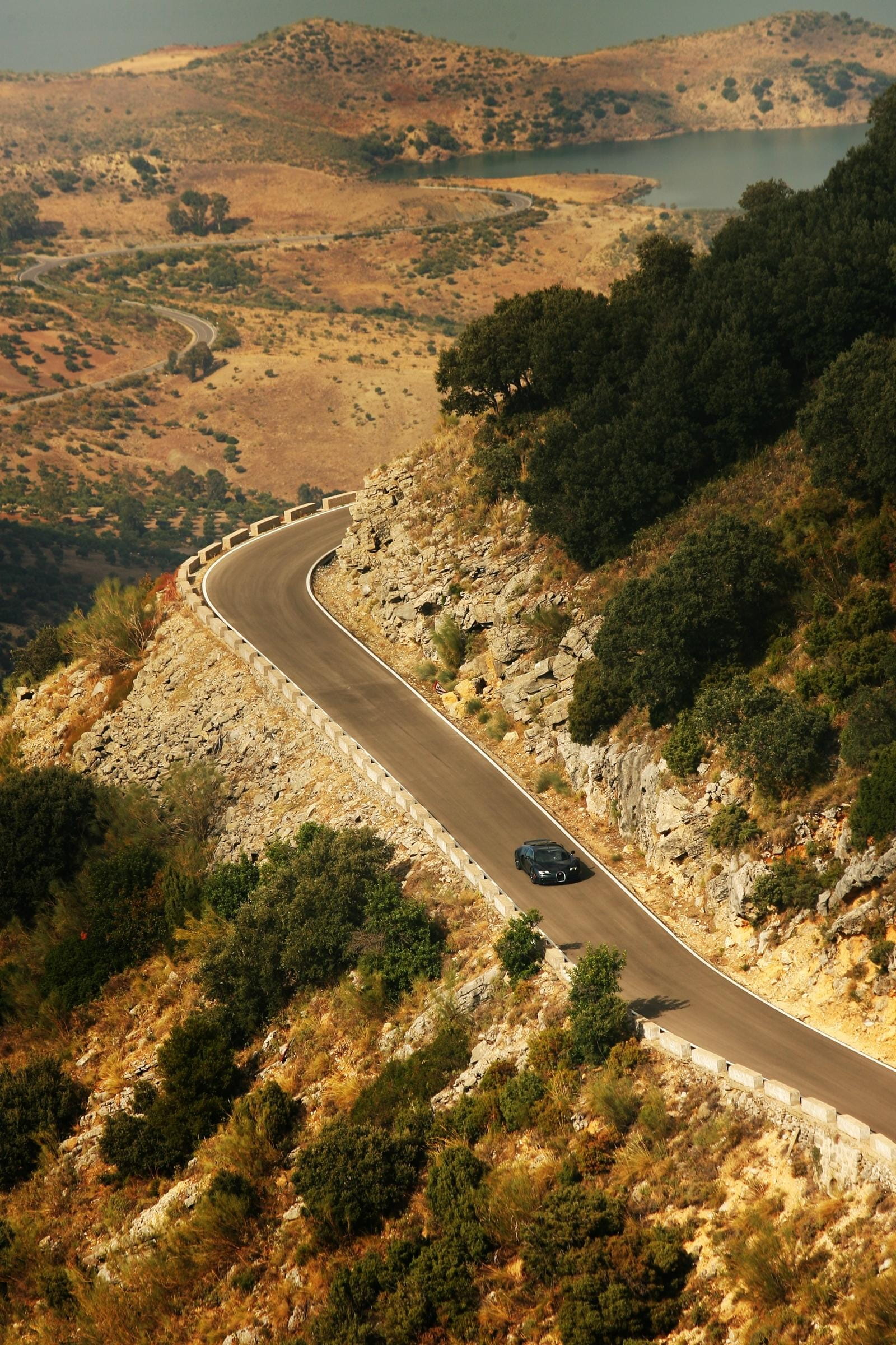 Vista aérea de un Bugatti Veyron en una carretera de montaña serpenteante.