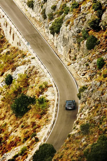 Vista aérea de un Bugatti Veyron tomando curvas en una carretera de montaña