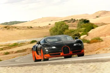 Bugatti Veyron en carretera rural, vista frontal y lateral.