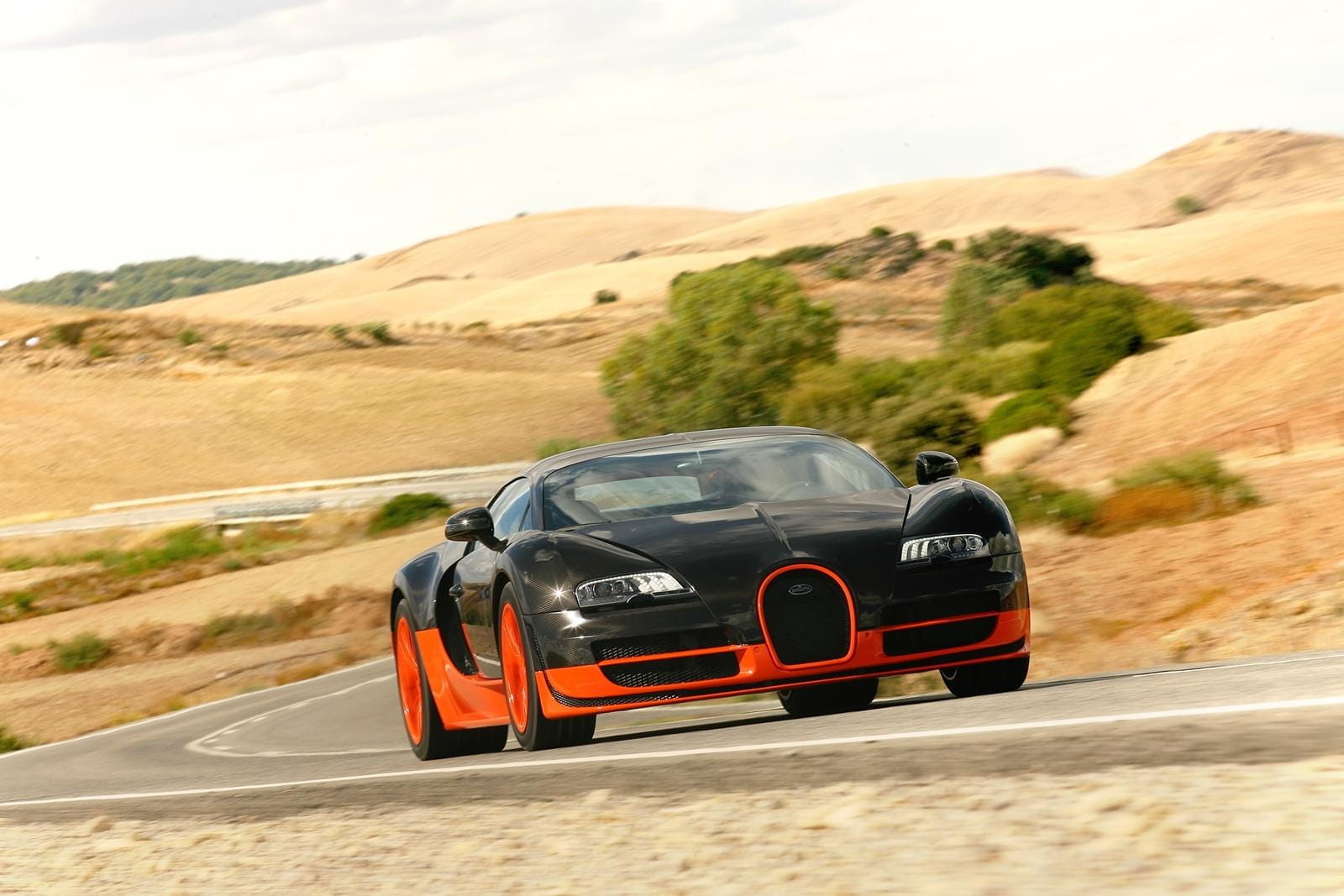 Bugatti Veyron en carretera rural, vista frontal y lateral.