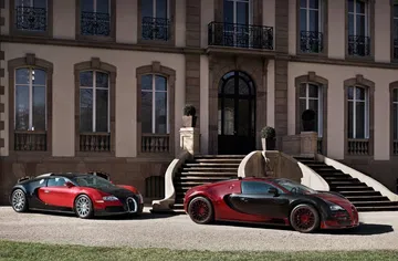 Dos Bugatti Veyron posan lateralmente frente a una elegante mansión.