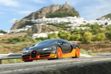 Vista lateral del Bugatti Veyron en movimiento, destacando su aerodinámica y diseño.