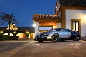 Vista lateral de un Bugatti Veyron al anochecer, mostrando su aerodinámica silueta.