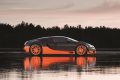 Bugatti Veyron capturado en perfil con majestuoso reflejo sobre el agua al atardecer.