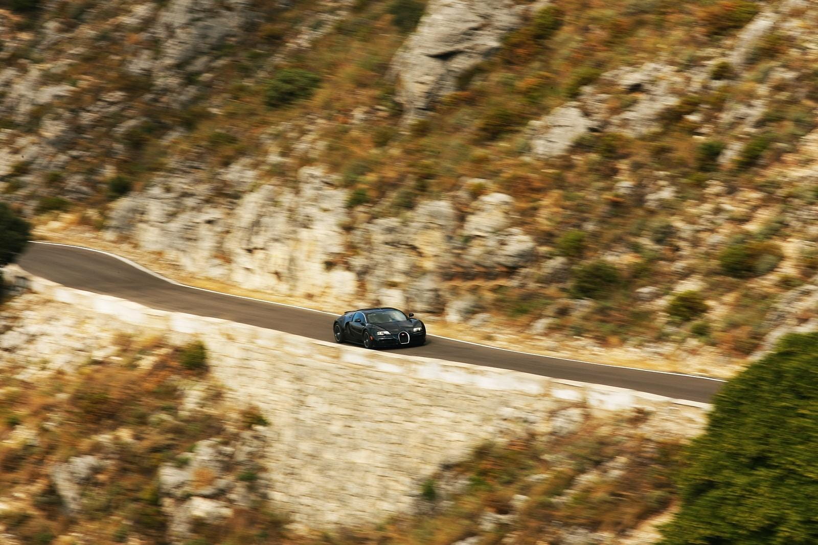 Vista lateral del Veyron circulando por una carretera de montaña.