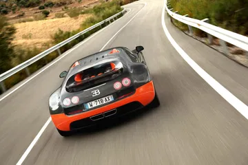Vista dinámica del Bugatti Veyron en pista, destacando su diseño aerodinámico.