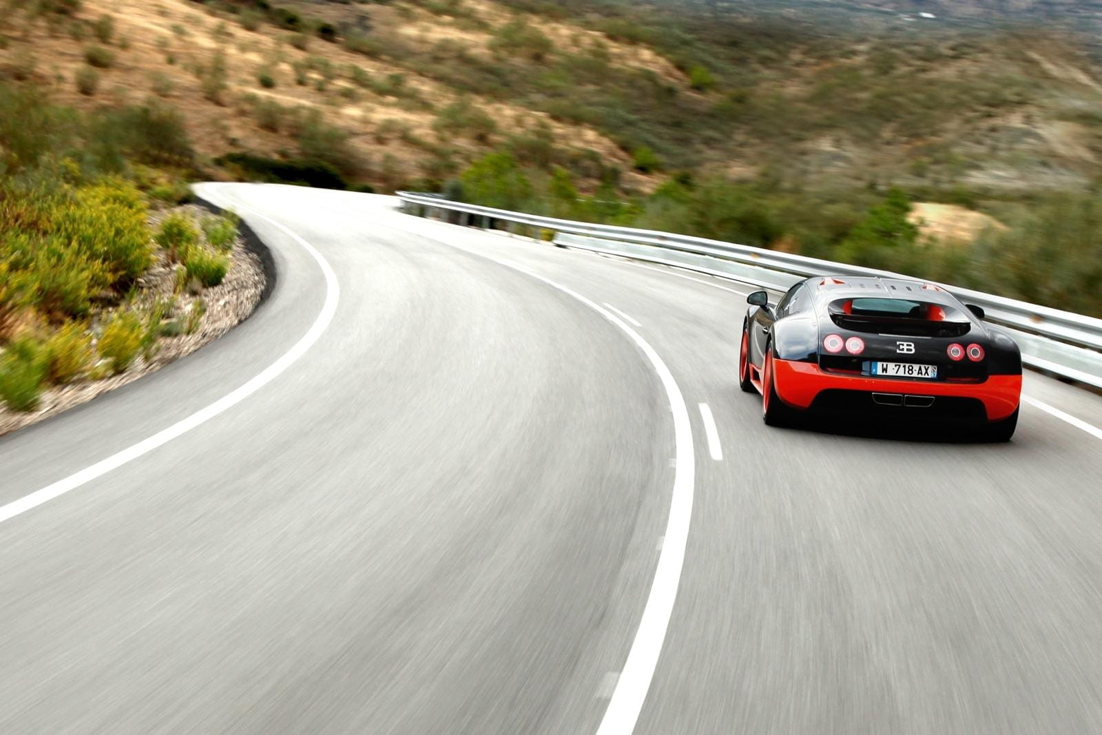 Vista dinámica de un Bugatti Veyron desde atrás, destacando su diseño aerodinámico.