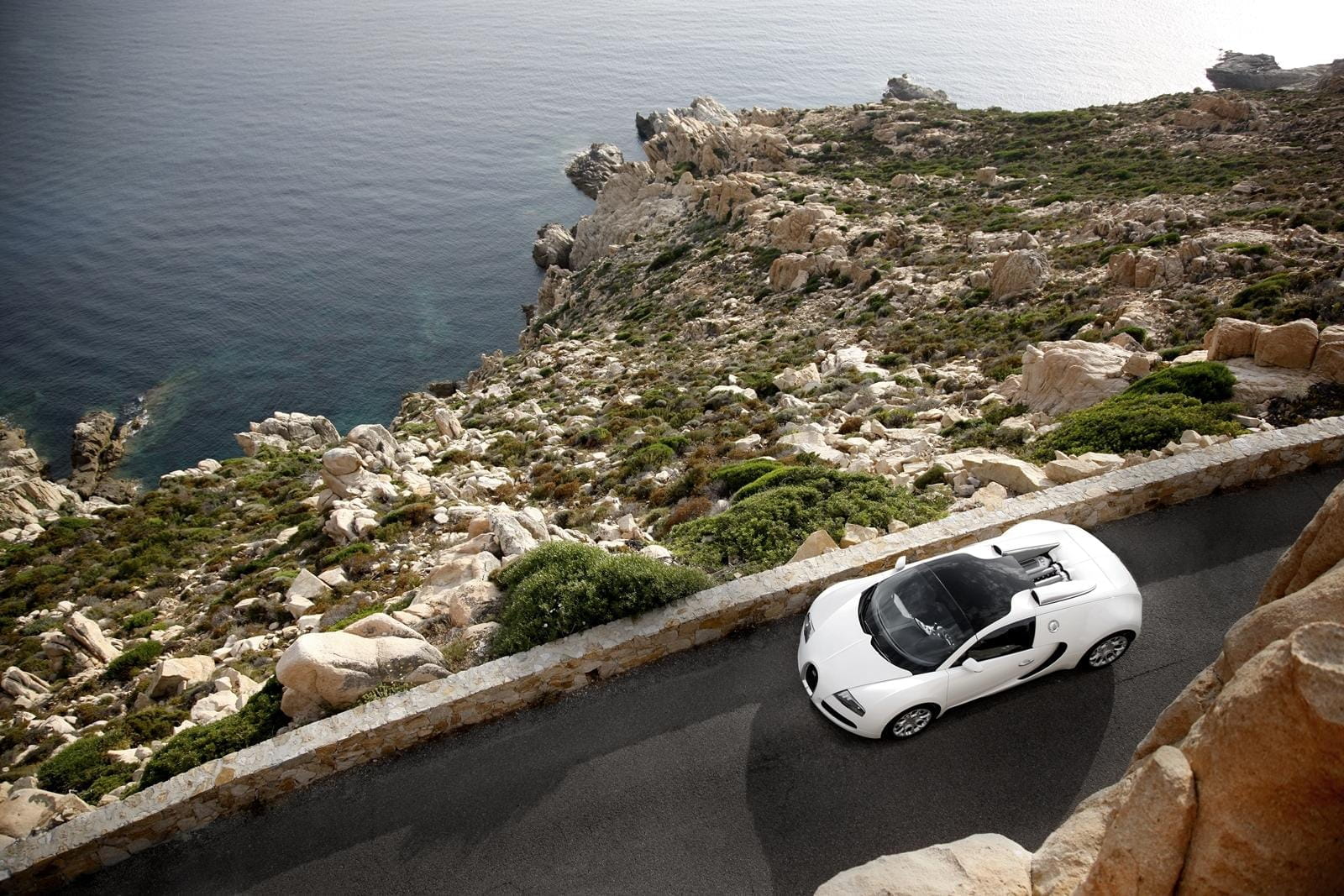 Vista aérea de un Bugatti Veyron circulando por carretera de costa.