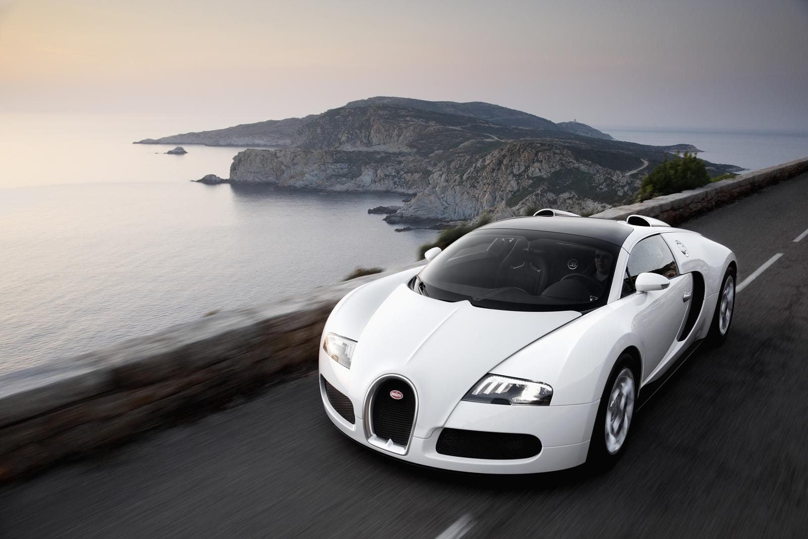Vista delantera y lateral del Bugatti Veyron con paisaje al atardecer.