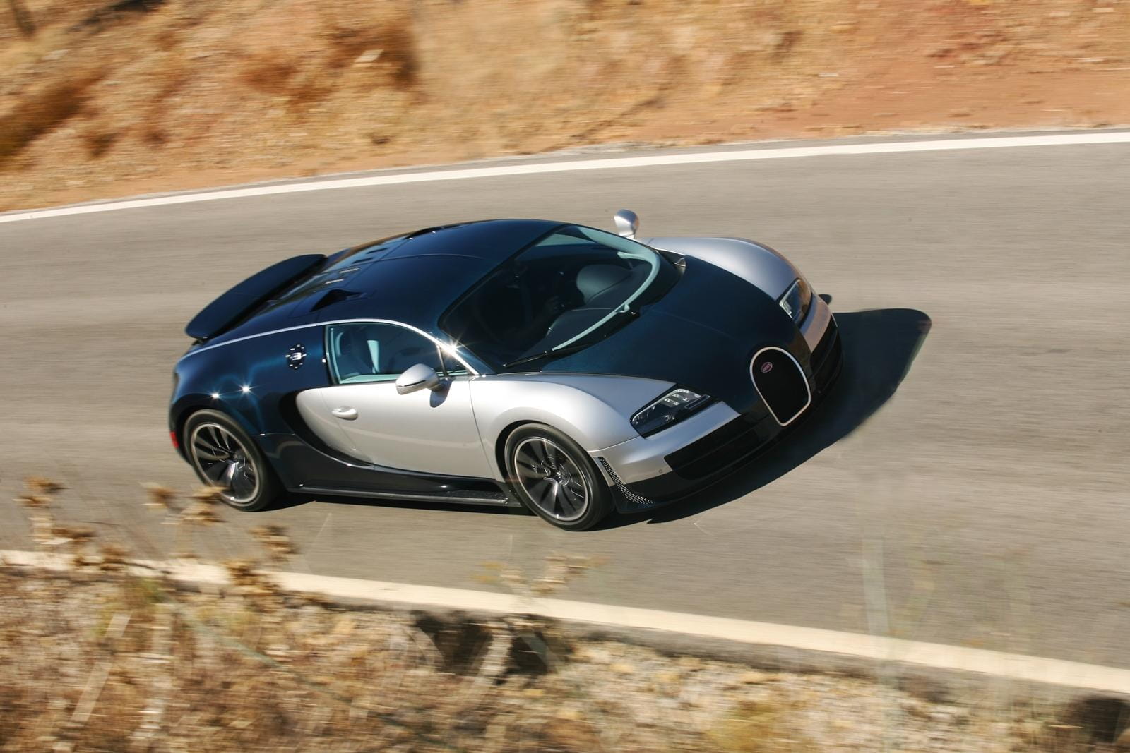 Vista lateral del Bugatti Veyron en plena aceleración, capturando su silueta aerodinámica.