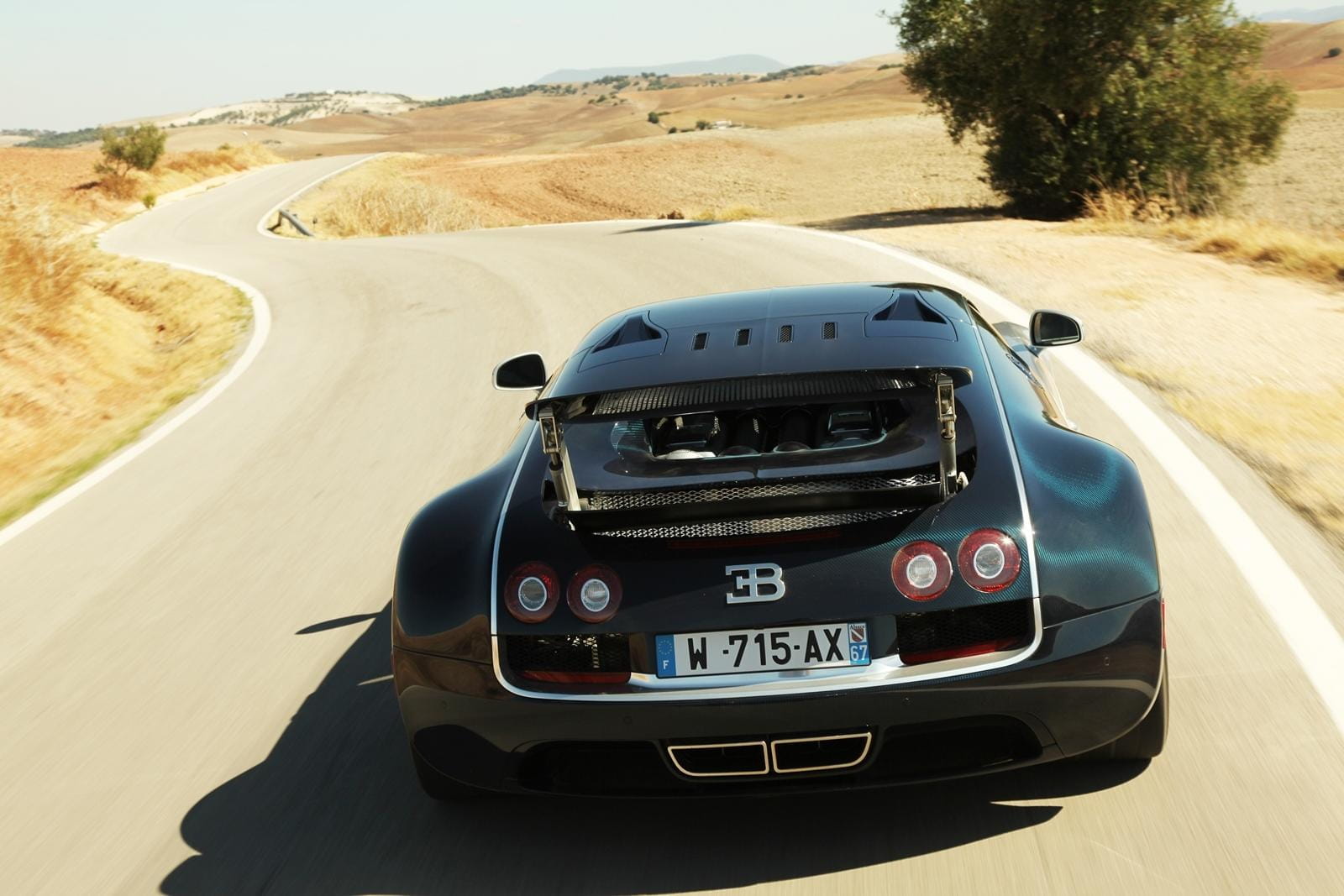 Vista trasera del Bugatti Veyron en carretera, destacando su diseño aerodinámico