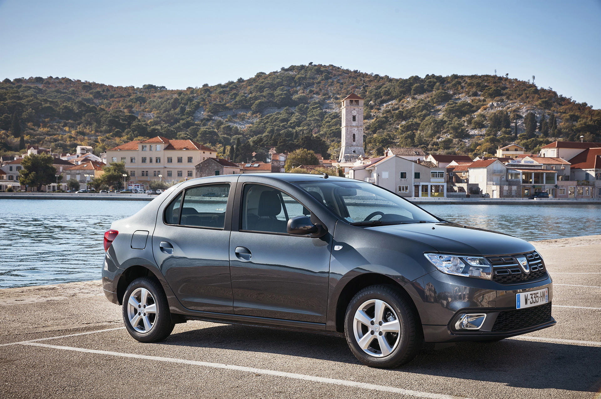 Vista lateral del Dacia Logan aparcado con vista al puerto.