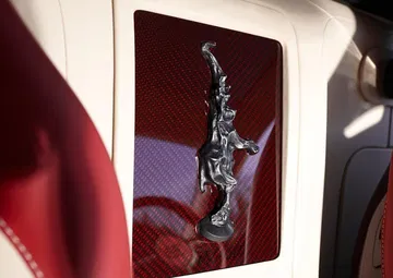 Emblema de Bugatti en relieve sobre marco rojo en el interior del vehículo.