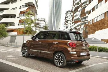 Vista lateral del Fiat 500L en un entorno urbano, destacando su diseño compacto.