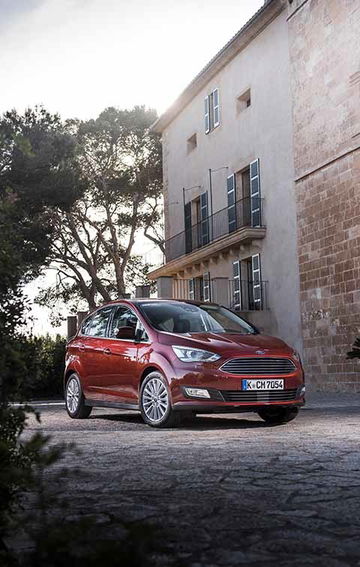 Vista angular del Ford C-MAX en un entorno urbano, destacando su diseño frontal y lateral.