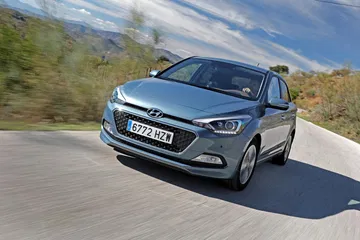 Vista de un Hyundai i20 en movimiento, destacando su diseño frontal y perfil.