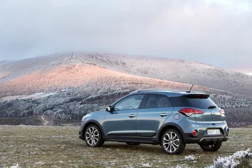 Vista lateral del Hyundai i20 con un paisaje montañoso al fondo.