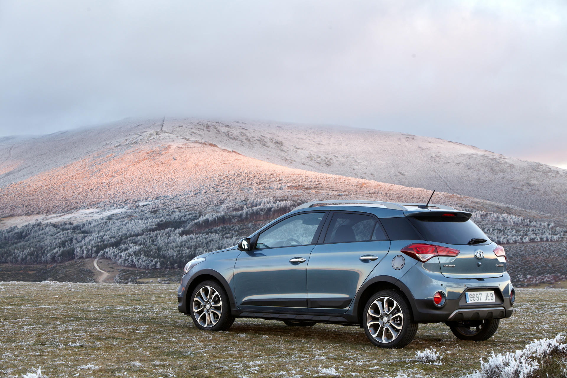 Vista lateral del Hyundai i20 con un paisaje montañoso al fondo.