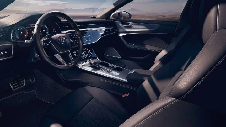 Vista lateral del elegante interior del Audi A6, destacando su consola y volante.
