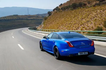 Vista lateral y trasera del Jaguar XJ en carretera, mostrando su silueta ágil.