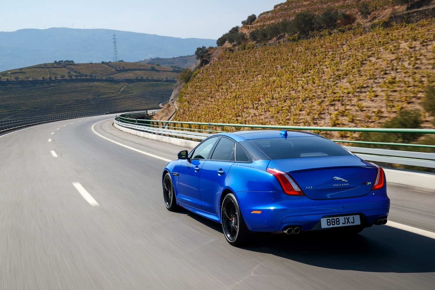 Vista lateral y trasera del Jaguar XJ en carretera, mostrando su silueta ágil.