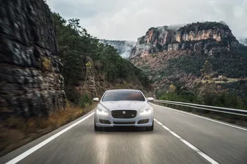 Vista frontal del Jaguar XJ en movimiento por carretera de montaña.