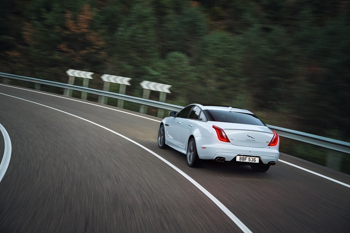 Vista dinámica del Jaguar XJ en carretera, enfatizando su elegante diseño trasero.