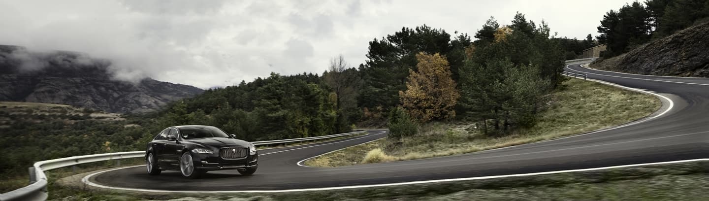Vista lateral de un Jaguar XJ en movimiento, destacando su diseño aerodinámico.