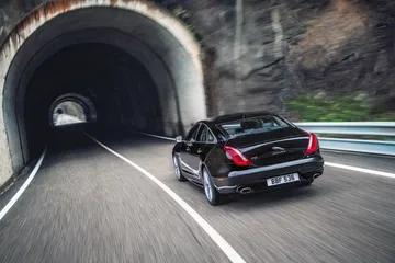 Vista dinámica del Jaguar XJ saliendo de un túnel, mostrando líneas elegantes.
