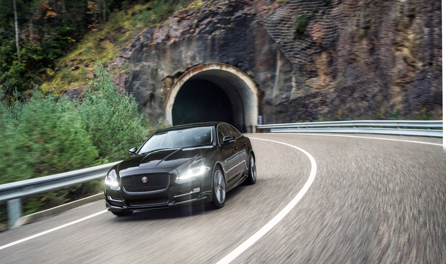 Vista dinámica del Jaguar XJ saliendo de un túnel, mostrando su elegante frontal.