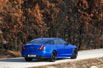 Vista dinámica del Jaguar XJ en su acabado azul vibrante, perfil trasero y lateral.