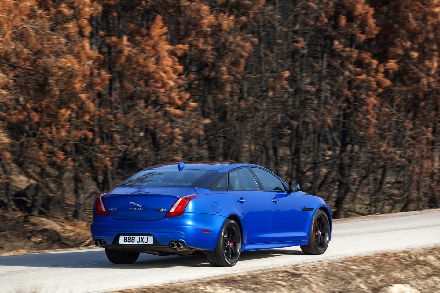 Vista dinámica del Jaguar XJ en su acabado azul vibrante, perfil trasero y lateral.