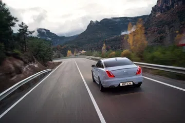 Vista trasera del Jaguar XJ en movimiento, destacando su diseño y luces traseras.