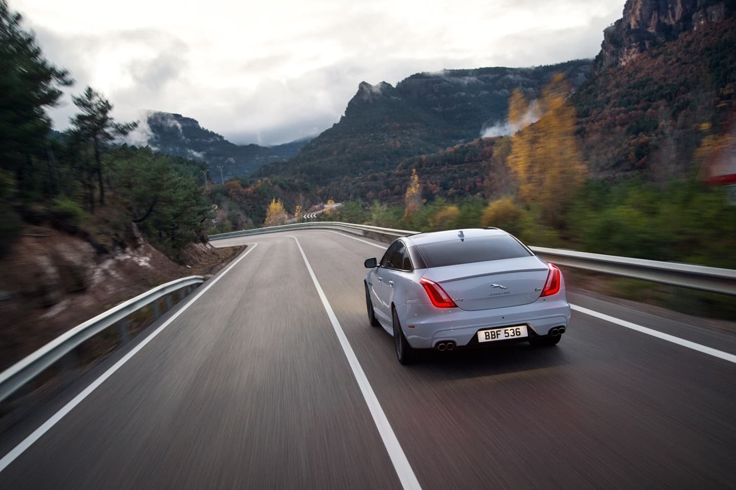 Vista trasera del Jaguar XJ en movimiento, destacando su diseño y luces traseras.