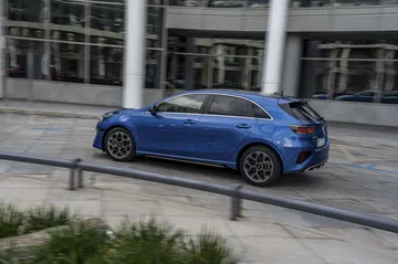 Kia Ceed captado en movimiento, destacando su perfil lateral deportivo.