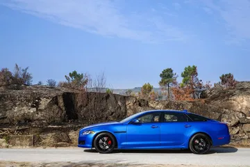 Vista lateral del Jaguar XJ en color azul metálico, realzando su diseño aerodinámico.