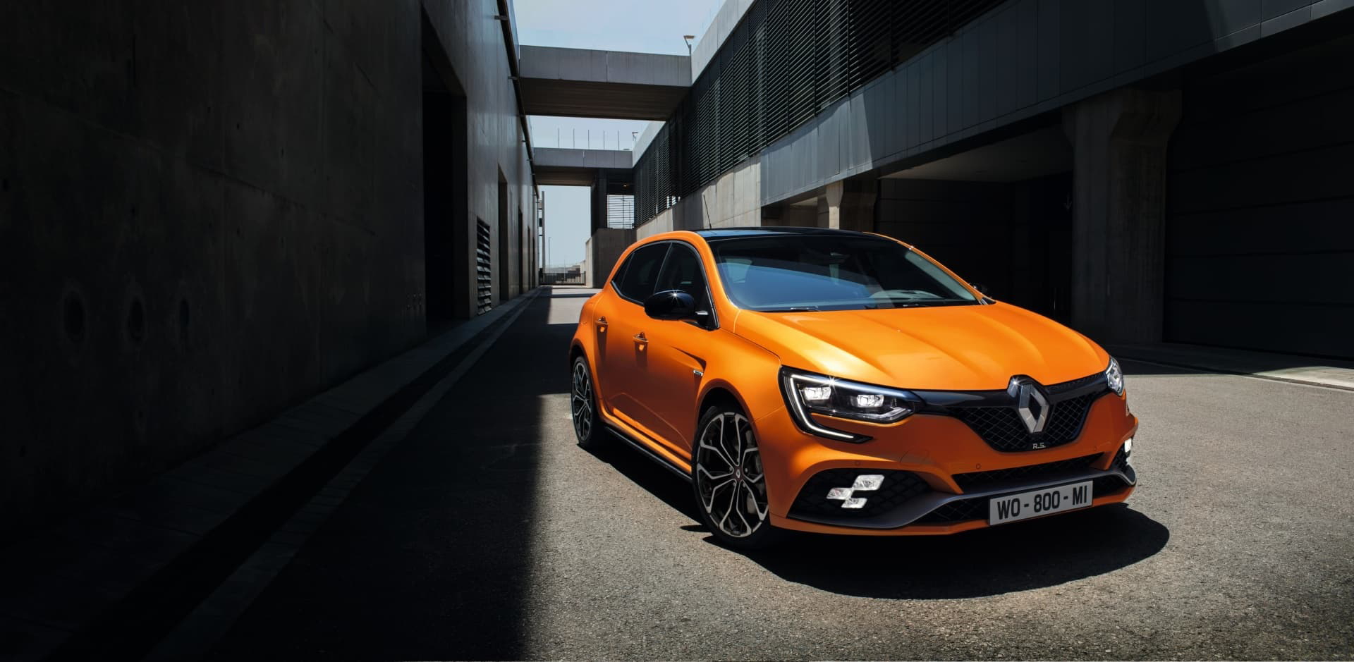 Renault Mégane en una potente tonalidad anaranjada, capturado desde un ángulo que resalta su diseño delantero y lateral.