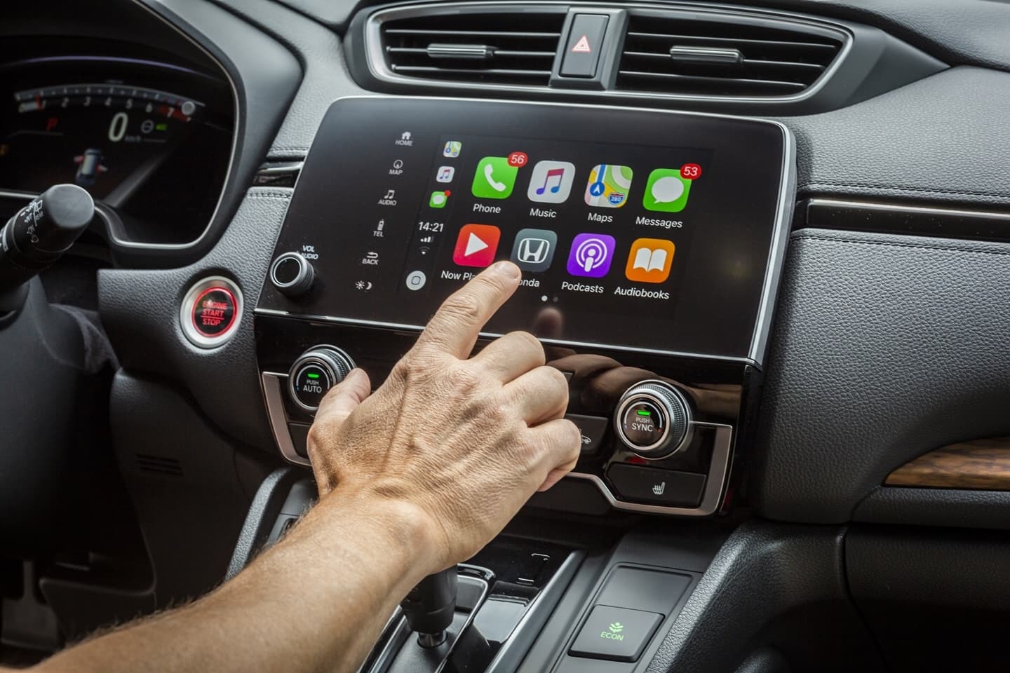 Vista del sistema de entretenimiento del Honda CR-V con una mano ajustando controles.