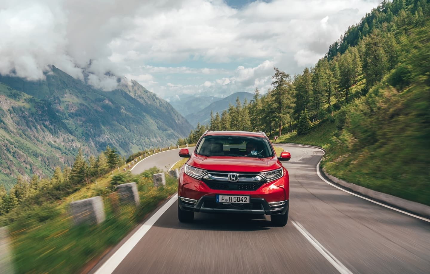 Honda CR-V en movimiento, vista frontal con paisaje montañoso.
