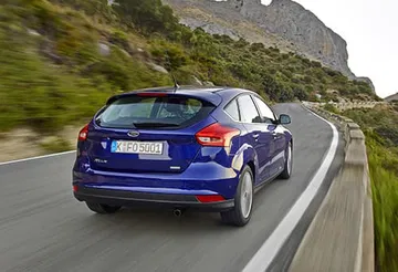 Vista dinámica de un Ford Focus mostrando su diseño trasero y lateral en carretera.