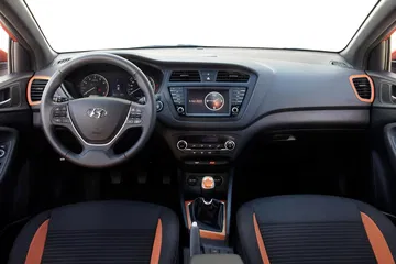 Vista del volante e instrumentación moderna del Hyundai i20, acabados en negro y naranja.