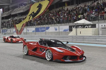 Vista lateral y delantera del Ferrari LaFerrari en pista nocturna, iluminando su diseño aerodinámico.