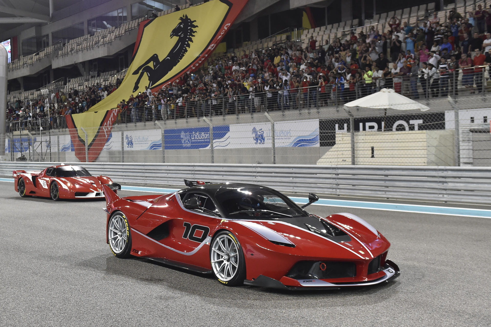 Vista lateral y delantera del Ferrari LaFerrari en pista nocturna, iluminando su diseño aerodinámico.