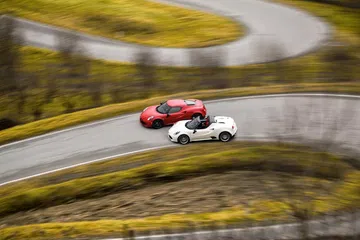 Dos Alfa Romeo 4C compitiendo en una carretera de montaña serpenteante.